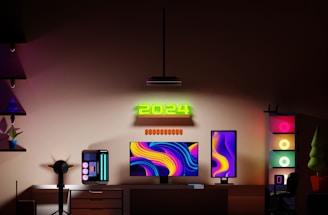 A modern gaming setup features a dual monitor arrangement with vibrant, abstract backgrounds. A glowing '2024' sign is mounted above the monitors. The desk includes a sleek gaming PC with LED accents, and the room is bathed in ambient lighting from multiple RGB light sources. Shelves with decorative items and a chair complete the workspace.