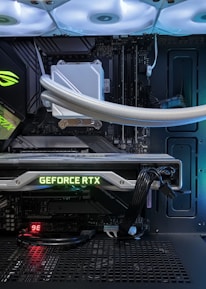 A high-end gaming or performance PC interior equipped with RGB lighting and multiple cooling fans. The graphics card prominently displayed is a GeForce RTX model, with branding visible. The setup includes neatly managed cables and a liquid cooling system.